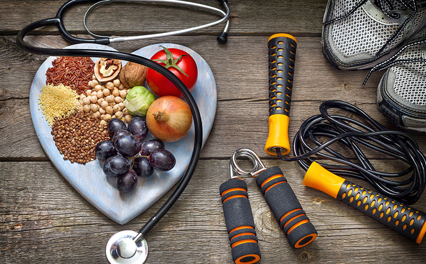 Healthy foods on a heart-shaped cutting board, surrounded by exercise equipment