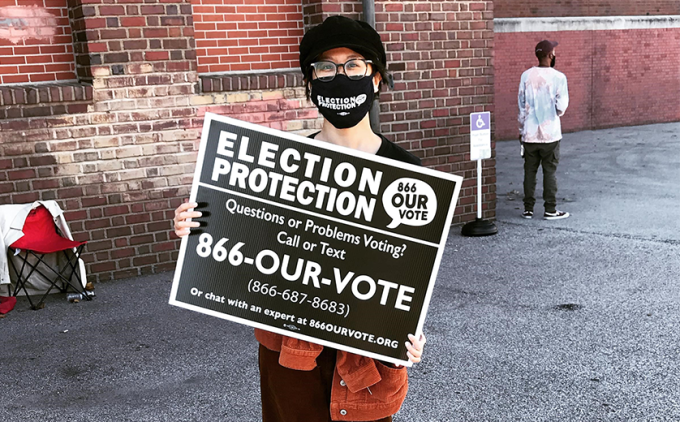 A volunteer outside a polling station during the November 3 election, holding a sign