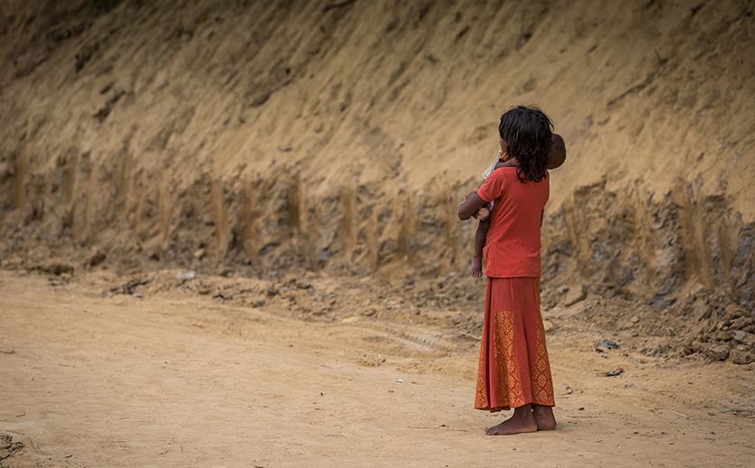 A young girl looks down a desert road in a refugee camp